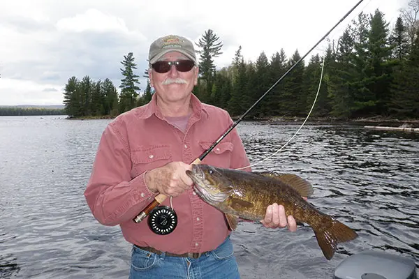 Bass fisherman with fly rod fishing in Maine.