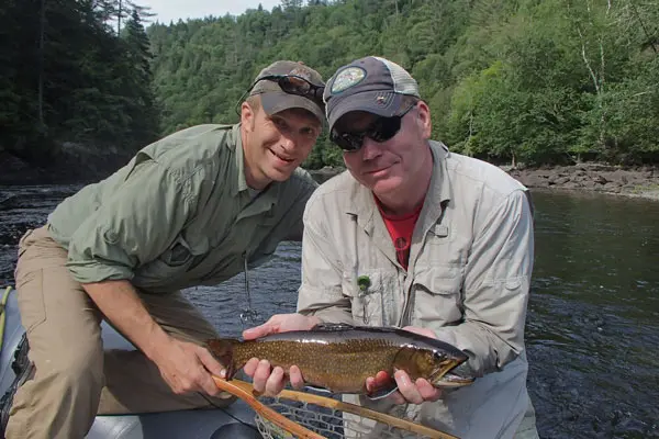 Maine fishing guide Mike and fisherman catch and release a fish on the Kennebec river in Maine.