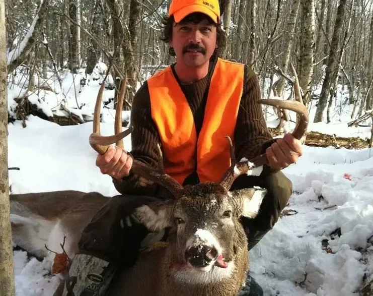 Scott Landry with harvest whitetail deer in snowy Maine woods.